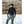 Person wearing a black POC back protector vest over a long sleeve shirt and grey ski pants in the snow