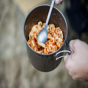 Snow Peak titanium pot filled with pasta and tomato sauce being stirred with a metal spoon