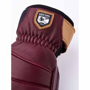 Close up of burgundy Hestra leather glove cuff with brand logo patch