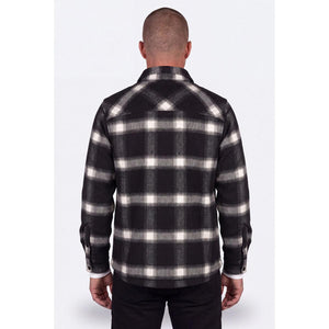 Back view of a man wearing a black and white plaid Mobile Warming flannel shirt