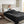 Person sitting on a bed covered by a dark grey plush electric blanket holding a mug