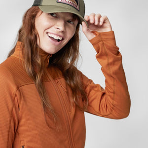 Person wearing a Fjallraven cap and an orange zip up fleece jacket