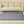 Grey quilted electric heating mat on a beige rug in front of a beige sofa