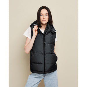 Woman wearing a black Kelvin hooded puffer vest over a white t-shirt and blue jeans