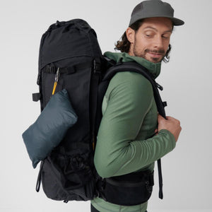Person wearing a black FjallRaven hiking backpack with a small blue pouch attached to the side