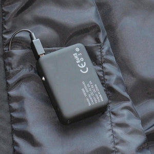 Black VB560 power bank with 6000mAh capacity connected to a charging cable inside a jacket pocket