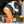 Worker in high visibility jacket and orange pants kneeling on ice while using tools