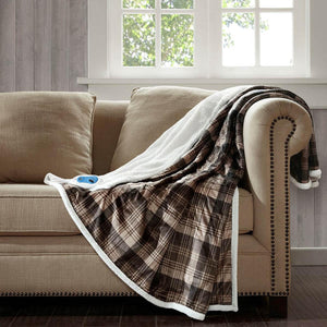 Woolrich brown plaid heated throw blanket with white sherpa lining draped over a beige sofa