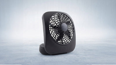 A black Treva portable fan with a spiral grille design, standing on a textured light blue surface.
