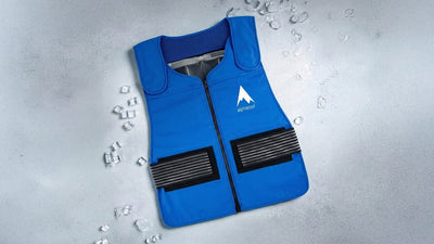 A blue Alphacool cooling vest, showing ice packs through an open zipper, lies on a light grey surface scattered with ice cubes. It has black strap details.