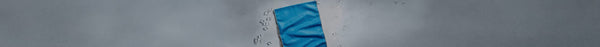 A vibrant blue cloth on a light gray surface, with scattered clear ice cubes and water droplets.