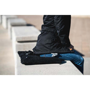 Person sitting on a black Tubes Canada fleece seat cushion on a concrete bench