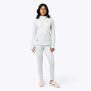 Woman wearing a light blue patterned quarter zip long sleeve top and matching leggings with beige sneakers
