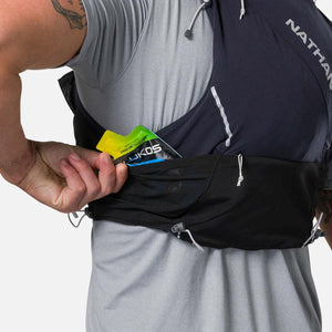 Person placing energy gel into the side pocket of a black Nathan hydration vest