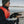 Man in a life vest holding a black and white dog on a boat