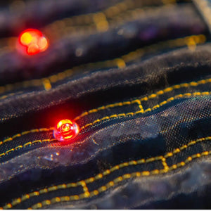 Close up of black fabric with yellow stitching and glowing red LED lights
