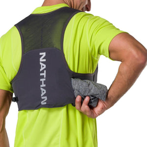 Person wearing a grey Nathan hydration vest over a neon yellow shirt with a grey garment in the back pocket