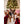 Person wearing Acorn tan slippers with faux fur lining sitting on a rug with a dog in front of a Christmas tree