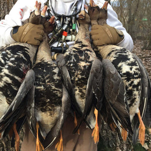 Hunter wearing tan Glacier Glove brand gloves holding four harvested geese