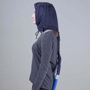 Person wearing a dark blue cooling therapy head wrap with a connected hose