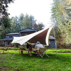 People sitting under a Snow Peak tarp in a backyard