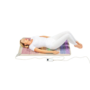 Person lying on a HealthyLine gemstone mat with LED lights and a digital controller