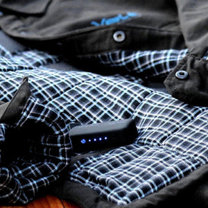 Volt Heat battery pack with blue LED indicator lights on a black and blue plaid jacket