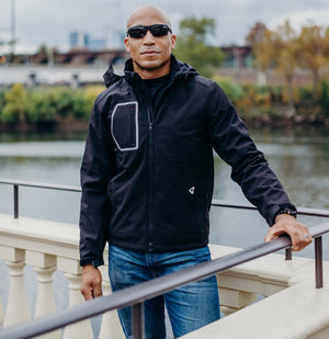 Man wearing a black Gerbing softshell jacket standing by a railing