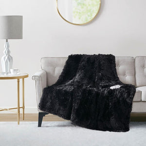 Serta black faux fur heated throw blanket draped over a light grey sofa