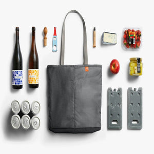 Bellroy tote bag surrounded by picnic items including wine bottles, canned drinks, fruit, cheese, and ice packs