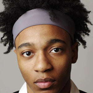 Close up portrait of a person with curly hair wearing a grey headband