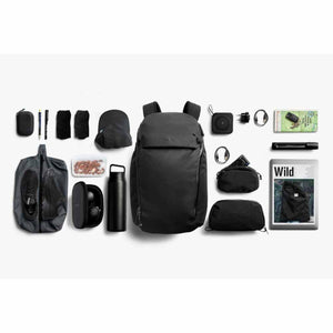 Bellroy backpack surrounded by organized travel accessories and personal items on a white background