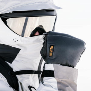 Person wearing Hestra black leather ski gloves with white jacket and ski goggles