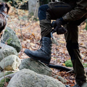 Arctic Volt black leather hiking boot on a rock in a forest