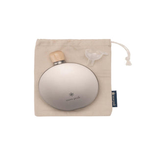 Snow Peak titanium flask with wooden cap and plastic funnel on a beige drawstring storage bag