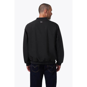 Back view of a man wearing a black Mobile Warming bomber jacket