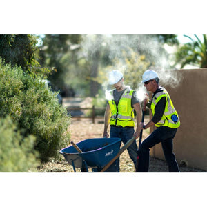 Two construction workers wearing ExtremeMIST cooling vests and hard hats while working outdoors