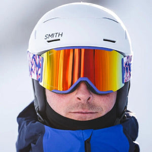 Person wearing a white Smith Optics helmet and goggles with a reflective orange lens