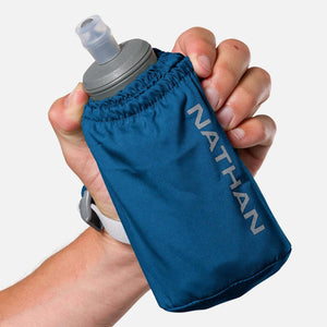 Hand holding a blue Nathan handheld water bottle with a grey cap
