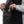 Person placing a lime green item into the internal pocket of a grey jacket