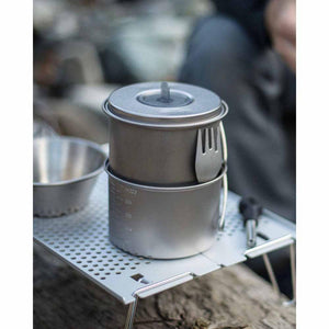 Titanium camping pot and lid with a spork attached on a portable metal table