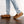 Person wearing light blue jeans and brown leather moccasin slippers with fleece lining