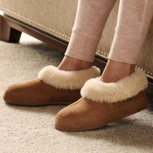 Acorn brown suede slippers with cream faux fur lining worn on feet