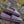 Acorn purple fleece slippers with patterned trim resting on grass