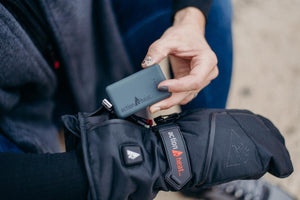 Person inserting an ActionHeat battery pack into a black heated glove