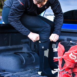 Person wearing ActionHeat black heated socks while sitting in a truck bed