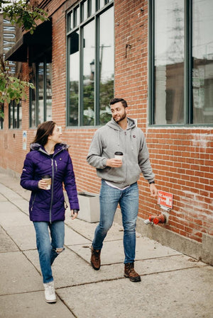 Man and woman walking on sidewalk holding coffee cups