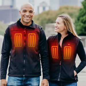 Man and woman wearing ActionHeat black heated vests with glowing chest heating elements