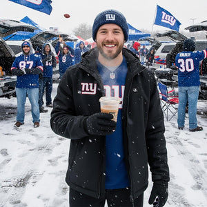 Man wearing ActionHeat jacket and New York Giants gear holding a hot drink in a snowy parking lot