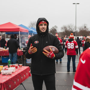 Man wearing ActionHeat San Francisco 49ers jacket and gloves holding a football at a tailgate